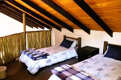 a bedroom with two beds and a wooden ceiling at Meerrus Self-Catering Home in Lake Chrissie