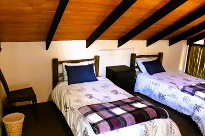 a bedroom with two beds and a wooden ceiling at Meerrus Self-Catering Home in Lake Chrissie