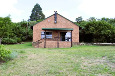 an old brick house in a grassy field at Meerrus Self-Catering Home in Lake Chrissie