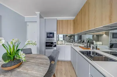 a kitchen with a wooden table and white cabinets at Lumina on 8th in Midrand