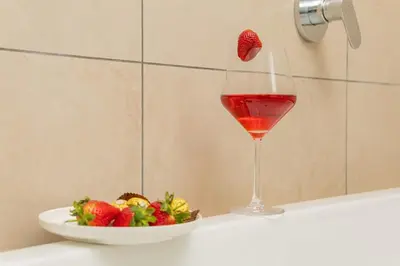 a glass of wine next to a bowl of strawberries and a plate of food at Lumina on 8th in Midrand