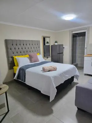 a bedroom with a large white bed with yellow pillows at Peshline Guest House Unit 0 in Ermelo