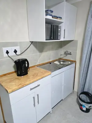 a small kitchen with white cabinets and a sink at Peshline Guest House Unit 0 in Ermelo