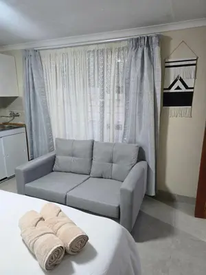 a living room with a couch in front of a window at Peshline Guest House Unit 0 in Ermelo