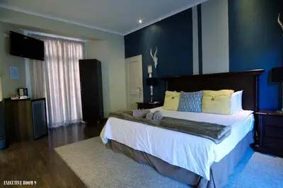 a bedroom with a large bed with blue walls at Cu Guest House in Phalaborwa