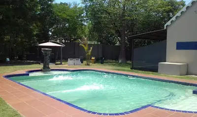 a swimming pool with a fountain in a yard at Cu Guest House in Phalaborwa