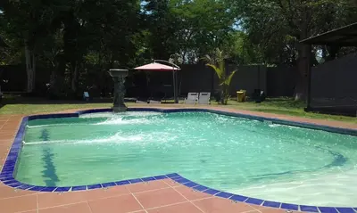 a swimming pool with a fountain in a yard at Cu Guest House in Phalaborwa