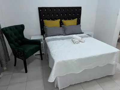 a bedroom with a bed and a green chair at Township Lodge -Seshego in Polokwane