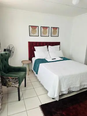 a bedroom with a bed and a green chair at Township Lodge -Seshego in Polokwane