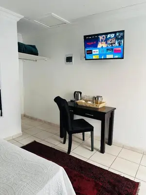 a black desk with a chair and a television on a wall at Township Lodge -Seshego in Polokwane