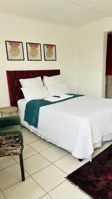 a bedroom with a large white bed and a chair at Township Lodge -Seshego in Polokwane