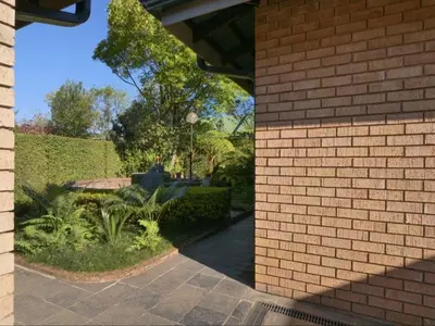 a brick building with a garden in the background at Forest and Ferns in Graskop