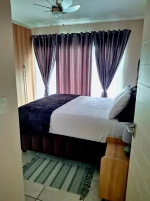 a bedroom with a bed with purple curtains and a window at The Blyde Couple Suite in Pretoria