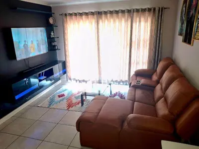 a living room with a brown couch and a television at The Blyde Couple Suite in Pretoria
