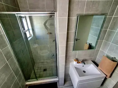 a bathroom with a shower and a sink and a mirror at The Blyde Couple Suite in Pretoria