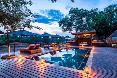 a swimming pool with lounge chairs and a wooden deck at Pafuri Camp by RETURN Africa in Makuleke Contract Park