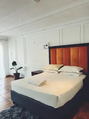 a bedroom with a large bed with a wooden headboard at Cozy stay in Kempton Park
