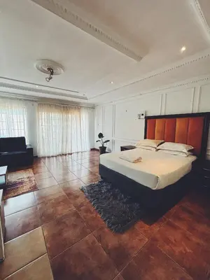 a bedroom with a large bed and a couch at Cozy stay in Kempton Park