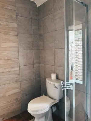 a bathroom with a toilet and a glass shower at Cozy stay in Kempton Park