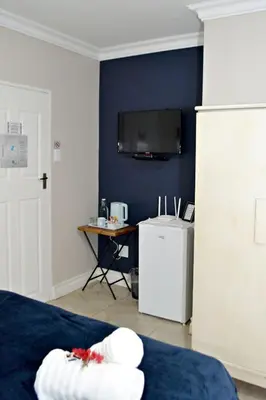 a room with a bed and a desk with a television at Bokmakierie Gastehuis Emalahleni Pty Ltd in Witbank