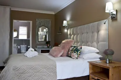 a bedroom with a large bed with a large headboard at Bokmakierie Gastehuis Emalahleni Pty Ltd in Witbank
