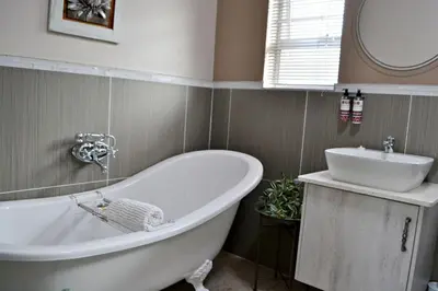 a bathroom with a white tub and a sink at Bokmakierie Gastehuis Emalahleni Pty Ltd in Witbank