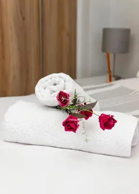 a white towel and roses on a bed at The Blyde 1471 in Pretoria