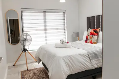 a bedroom with a bed with a fan and a window at The Blyde 1471 in Pretoria