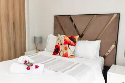 a bedroom with two beds with white sheets and flowers at The Blyde 1471 in Pretoria