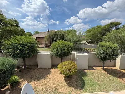 a yard with a fence and trees and a house at Bananas Den in Sandton