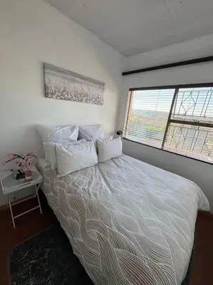 a bedroom with a bed with white sheets and a window at Bananas Den in Sandton