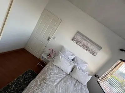 a bedroom with a bed with white pillows and a door at Bananas Den in Sandton