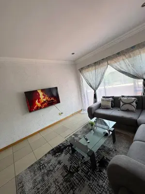 a living room with a fire painting on the wall at Bananas Den in Sandton
