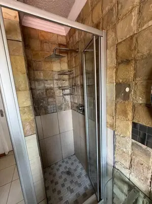 a shower with a glass door in a bathroom at Bananas Den in Sandton