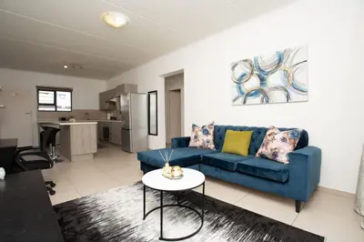 a living room with a blue couch and a table at Mercy land Apartment 1 in Midrand