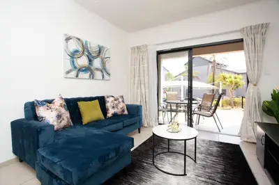 a living room with a blue couch and a table at Mercy land Apartment 1 in Midrand