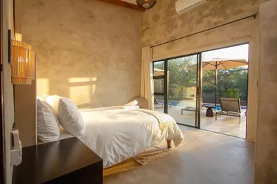 a bedroom with a bed and a sliding glass door at The Duke Luxury Safari Villa, Huge Pool, Giraffe-Feeding-Tower, Outdoor Shower in Marloth Park