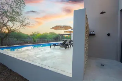 a pool with a table and chairs and an umbrella at The Duke Luxury Safari Villa, Huge Pool, Giraffe-Feeding-Tower, Outdoor Shower in Marloth Park