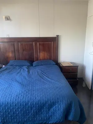 a bedroom with a blue bed with a wooden headboard at One Bedroom Apartment at Menlyn Place in Pretoria