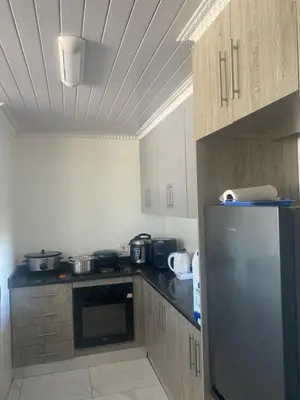 a kitchen with wooden cabinets and a stainless steel refrigerator at One Bedroom Apartment at Menlyn Place in Pretoria