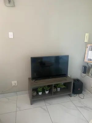 a flat screen tv sitting on top of a wooden entertainment center at One Bedroom Apartment at Menlyn Place in Pretoria