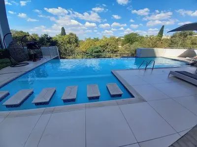 a large swimming pool with four chairs at 522 The Regency Menlyn in Pretoria