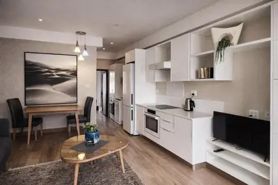 a kitchen with white cabinets and a table in a room at 522 The Regency Menlyn in Pretoria