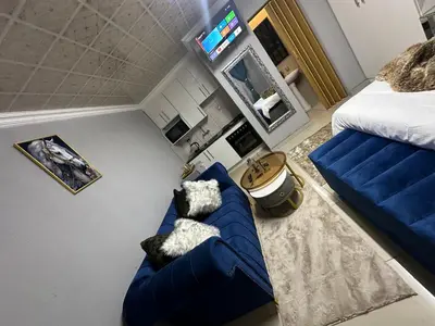 a living room with a blue couch and a bed at StayComfyGuesthouseByPunky in Soshanguve