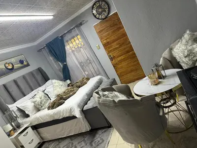 a room with a bed and a table and a clock at StayComfyGuesthouseByPunky in Soshanguve