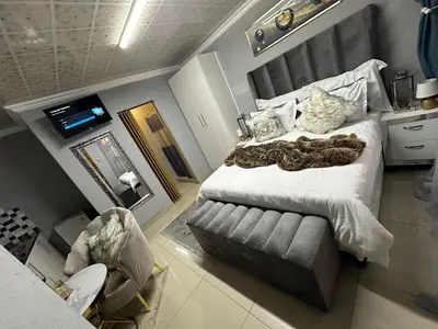 a bedroom with a large bed and a couch at StayComfyGuesthouseByPunky in Soshanguve