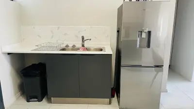 a kitchen with a sink and a refrigerator at Luxury Apartment at 93 on New in Midrand