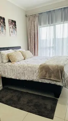 a bedroom with a large bed with a window at Luxury Apartment at 93 on New in Midrand