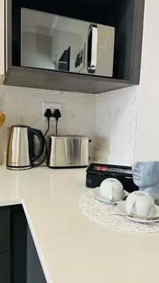 a kitchen counter with two dishes and a microwave at Luxury Apartment at 93 on New in Midrand