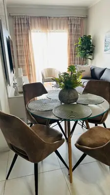 a living room with a table with chairs and a couch at Luxury Apartment at 93 on New in Midrand